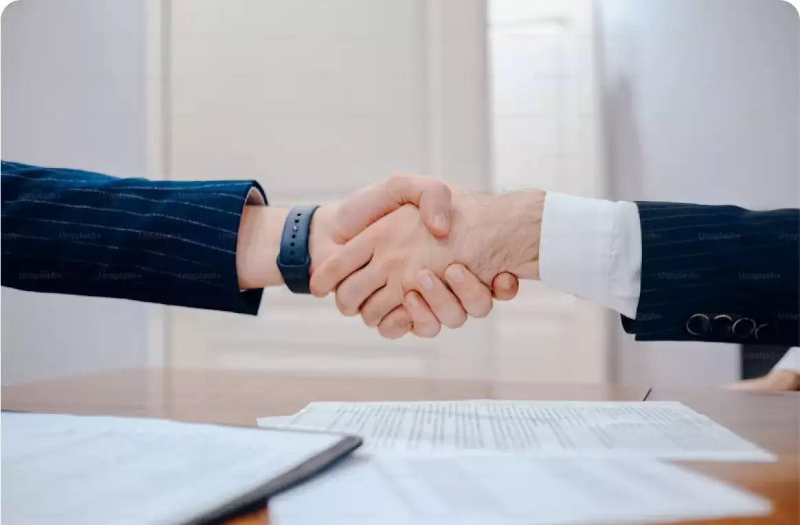 Two people shaking hands over a table