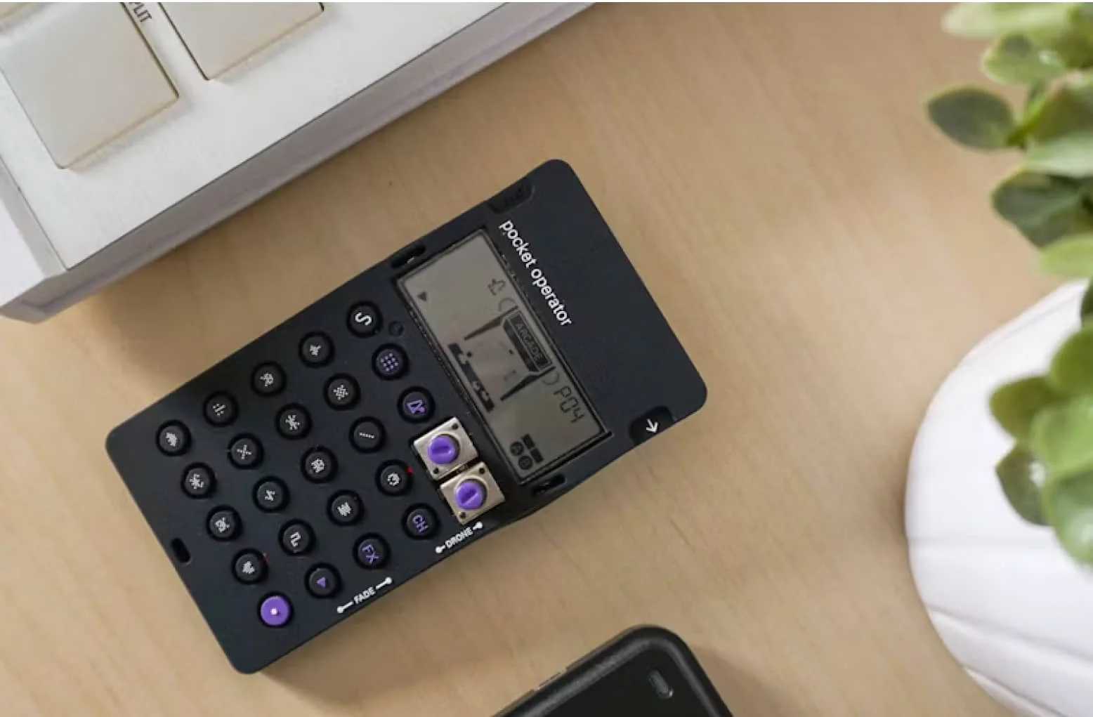 A black calculator sitting on top of a wooden table.