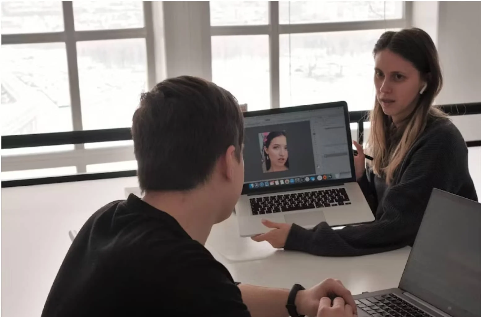 A man and woman sitting at a table with a laptop.