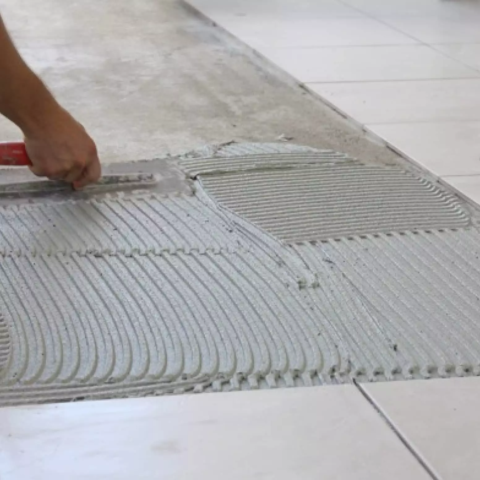 A person is laying tile on the floor