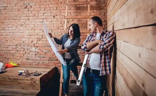 A man and woman looking at plans in a room.